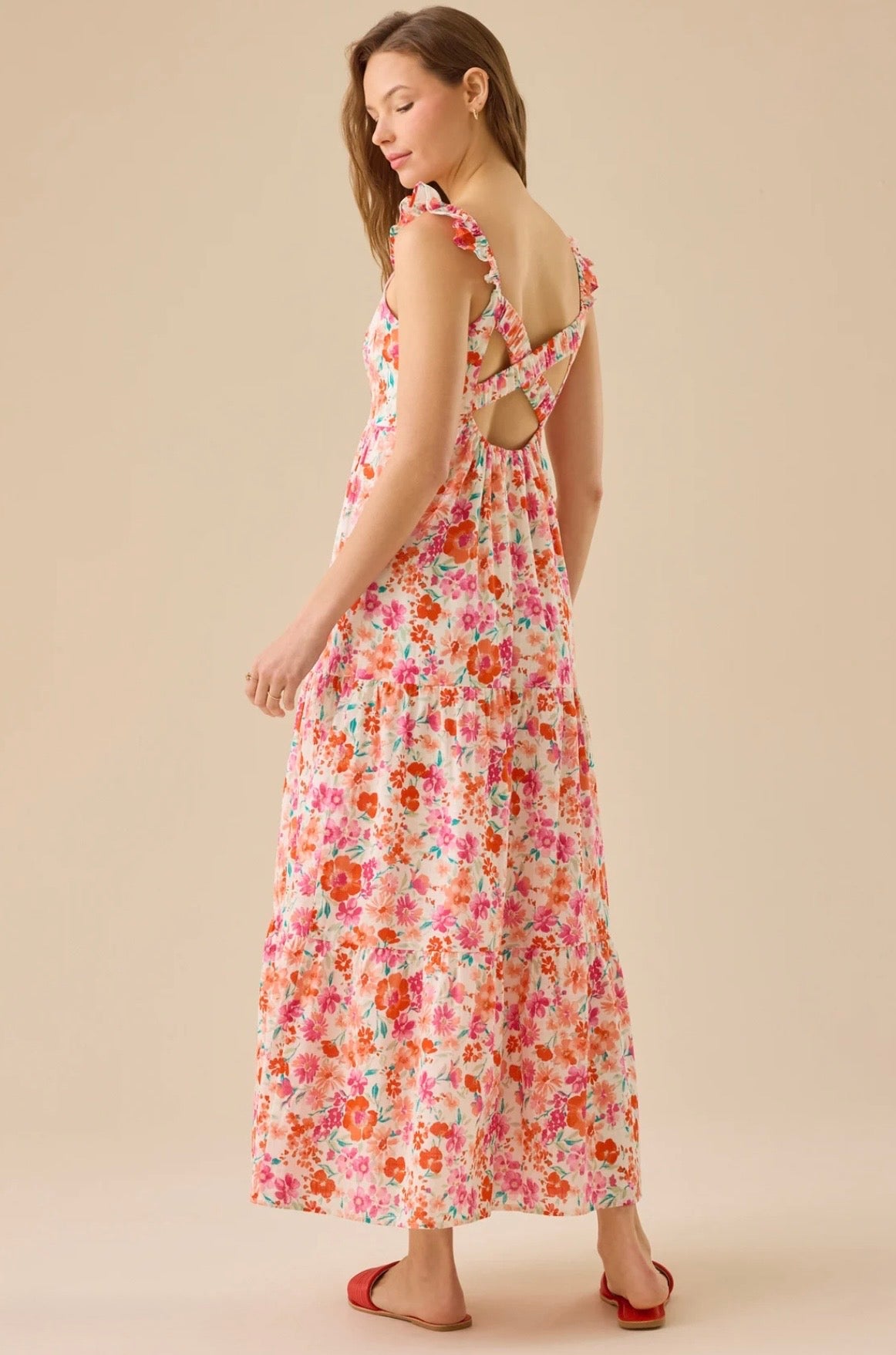 Woman wearing a floral dress with cut-out back on a beige background