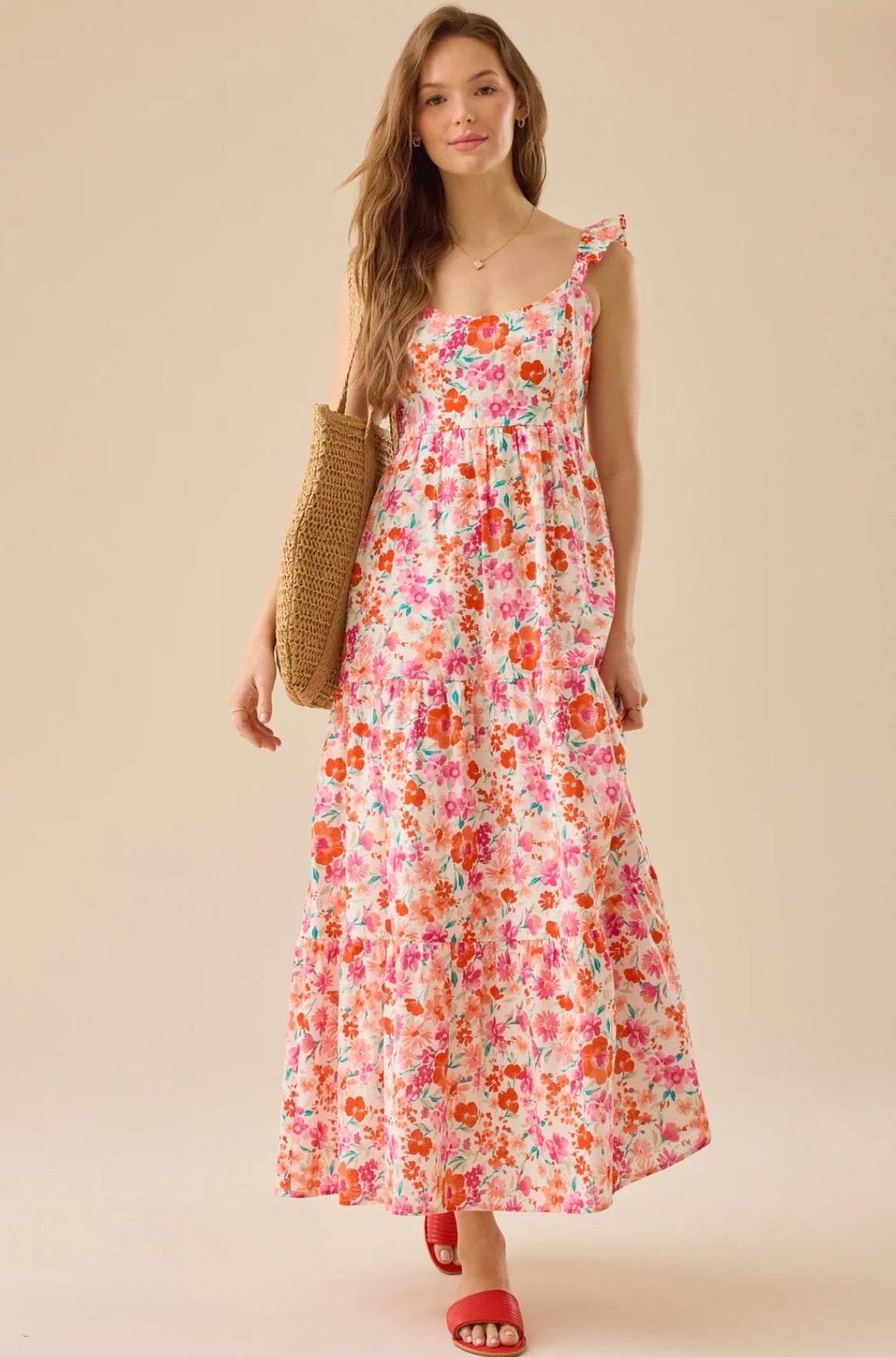 Woman wearing a floral dress holding a straw bag on a beige background